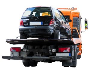 Wrecked car next to flatbed tow truck